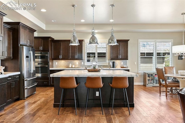 kitchen featuring appliances with stainless steel finishes, decorative light fixtures, and a center island