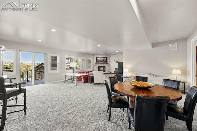 carpeted dining room featuring a stone fireplace