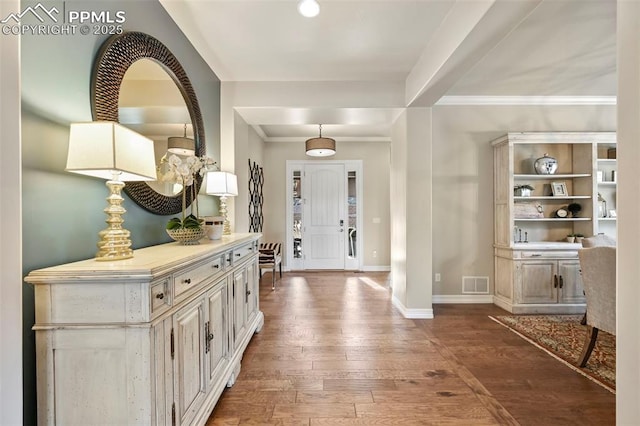 foyer entrance with crown molding and dark hardwood / wood-style flooring