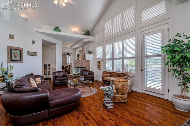 living room featuring hardwood / wood-style floors, a tile fireplace, high vaulted ceiling, and ceiling fan