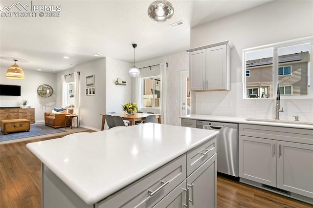 kitchen featuring a kitchen island, dishwasher, sink, gray cabinetry, and hanging light fixtures