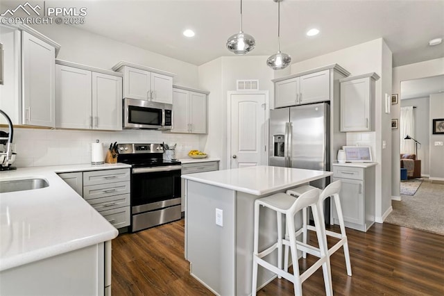 kitchen with pendant lighting, backsplash, stainless steel appliances, and a kitchen island