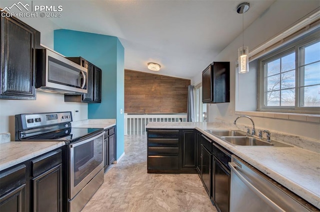 kitchen with lofted ceiling, sink, wooden walls, pendant lighting, and stainless steel appliances