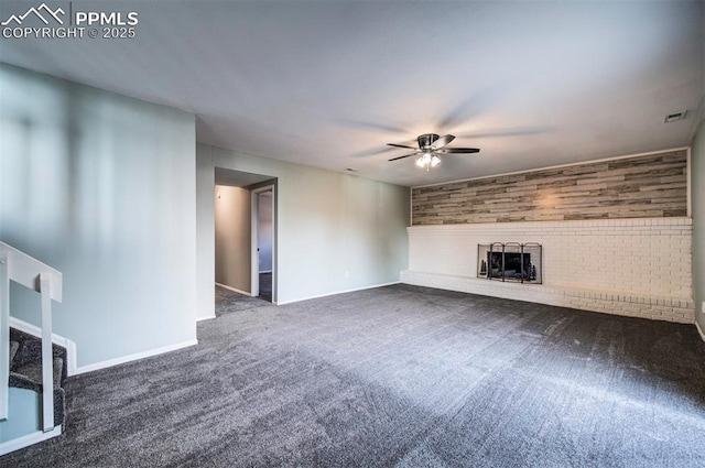 unfurnished living room featuring dark colored carpet, a brick fireplace, and ceiling fan