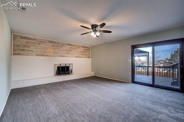 unfurnished living room with carpet, wood walls, ceiling fan, and a brick fireplace