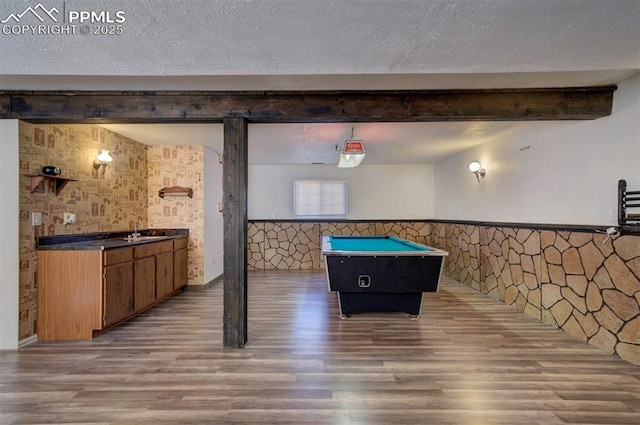 recreation room with beamed ceiling, sink, a textured ceiling, and hardwood / wood-style flooring