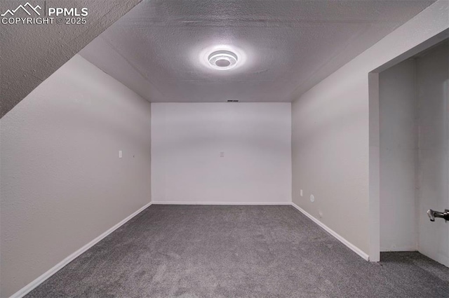 additional living space featuring a textured ceiling and dark carpet