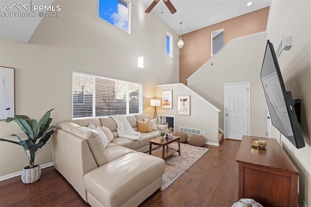 living room with dark hardwood / wood-style floors, ceiling fan, and a towering ceiling