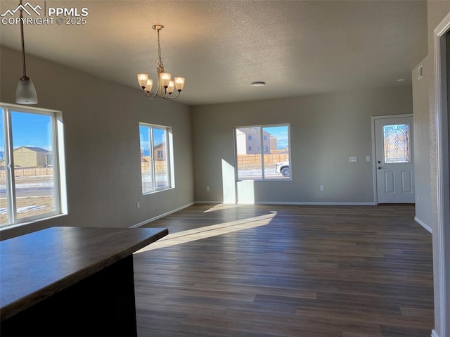 unfurnished dining area with dark hardwood / wood-style flooring, a chandelier, and a textured ceiling