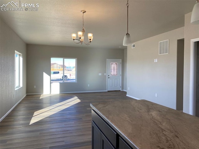 kitchen featuring hanging light fixtures, dark wood-type flooring, a notable chandelier, and a textured ceiling