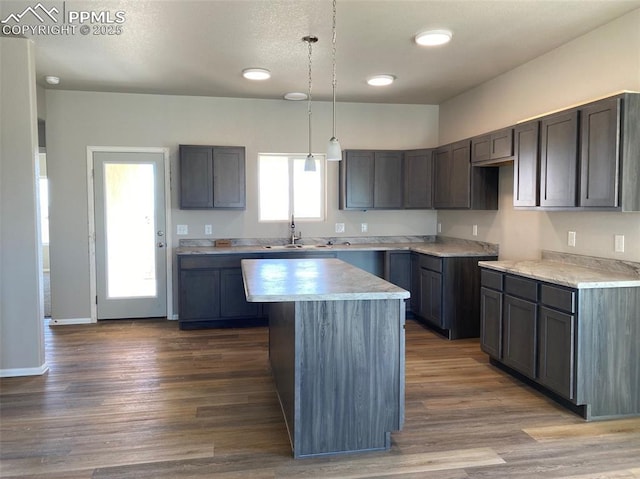 kitchen with hardwood / wood-style flooring, a center island, sink, and decorative light fixtures