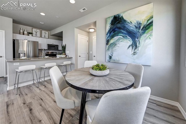 dining room featuring sink and light hardwood / wood-style flooring