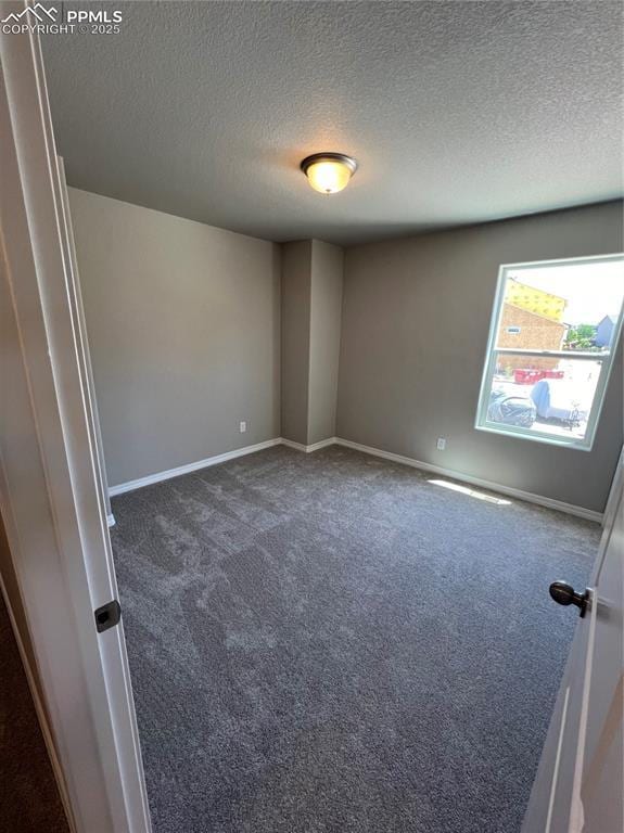 carpeted empty room featuring a textured ceiling