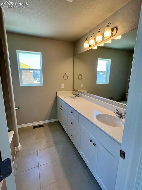 bathroom with tile patterned flooring, vanity, and a textured ceiling