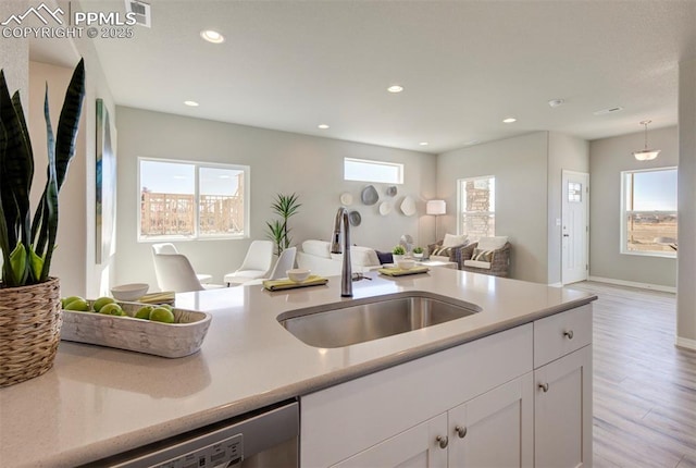 kitchen with a healthy amount of sunlight, sink, white cabinets, and light hardwood / wood-style floors