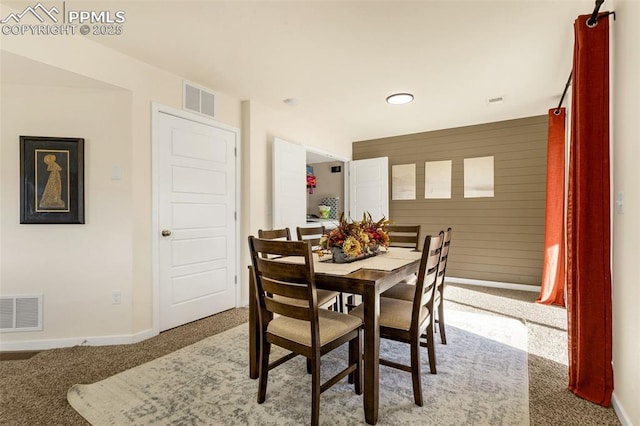 dining room featuring carpet floors and wooden walls