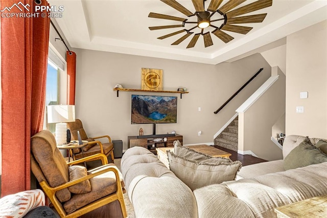 living room with ceiling fan, wood-type flooring, and a tray ceiling