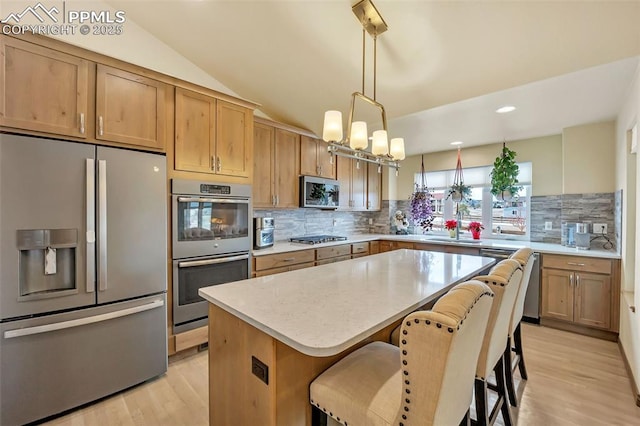 kitchen with decorative light fixtures, lofted ceiling, decorative backsplash, a center island, and stainless steel appliances