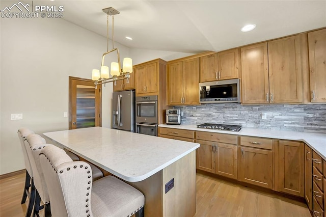 kitchen featuring pendant lighting, lofted ceiling, a breakfast bar area, appliances with stainless steel finishes, and decorative backsplash