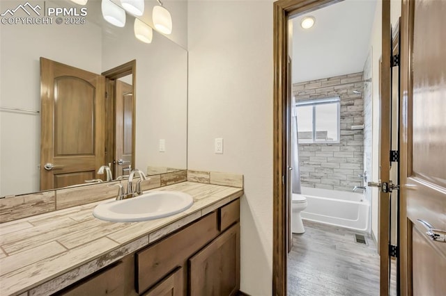 full bathroom with vanity, tiled shower / bath combo, wood-type flooring, and toilet