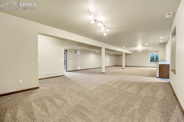 basement featuring light carpet and a textured ceiling