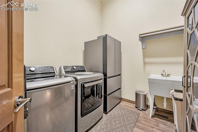 clothes washing area with light hardwood / wood-style floors and washing machine and dryer