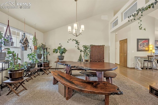 dining area with a notable chandelier, wood-type flooring, and high vaulted ceiling