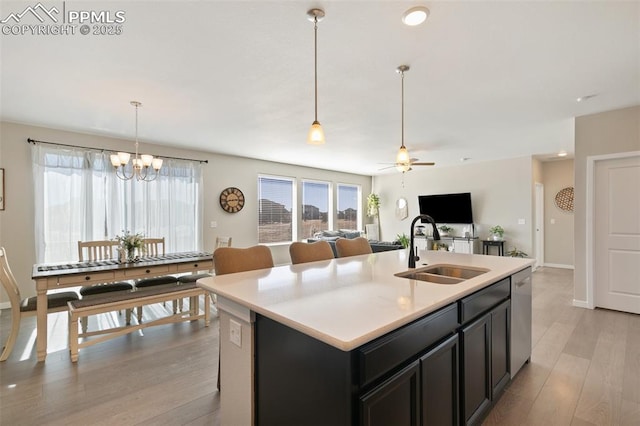 kitchen with dishwasher, sink, hanging light fixtures, a kitchen island with sink, and light hardwood / wood-style floors