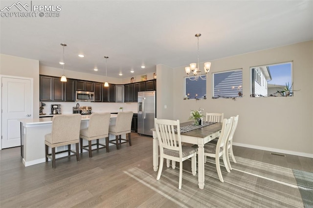 dining space with an inviting chandelier and light hardwood / wood-style flooring