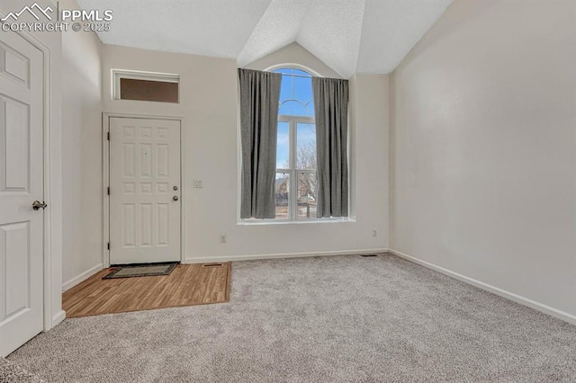 entrance foyer with carpet floors, vaulted ceiling, a textured ceiling, and baseboards