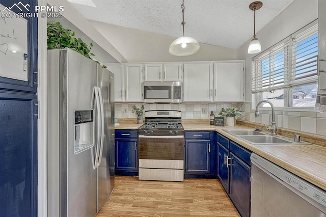 kitchen featuring lofted ceiling, blue cabinets, stainless steel appliances, a sink, and light wood-type flooring