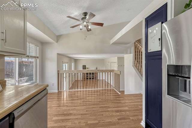 kitchen with a ceiling fan, blue cabinets, stainless steel appliances, a textured ceiling, and light wood-style floors