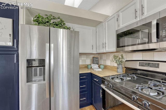 kitchen featuring white cabinetry, light countertops, appliances with stainless steel finishes, blue cabinetry, and backsplash