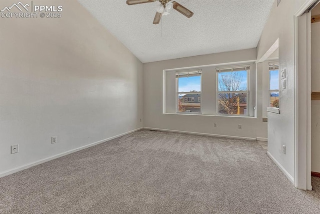 carpeted spare room featuring a ceiling fan, lofted ceiling, a textured ceiling, and baseboards