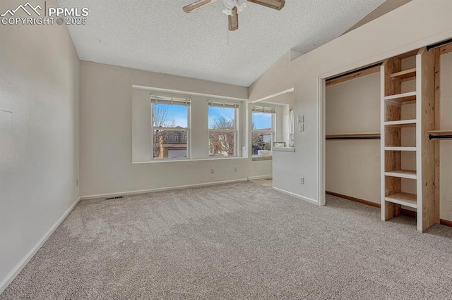 unfurnished bedroom featuring carpet, a ceiling fan, vaulted ceiling, a textured ceiling, and baseboards