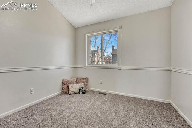 unfurnished room with carpet floors, visible vents, a textured ceiling, and baseboards