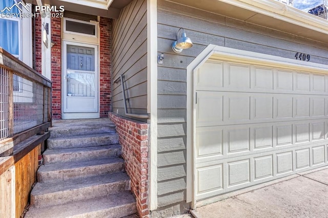 entrance to property with a garage and brick siding