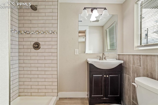 bathroom featuring tiled shower, toilet, tile walls, vanity, and hardwood / wood-style floors