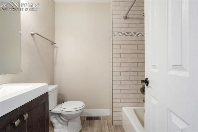 full bathroom with tiled shower / bath combo, vanity, hardwood / wood-style floors, and toilet