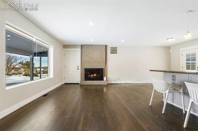 unfurnished living room featuring dark wood-type flooring and a brick fireplace