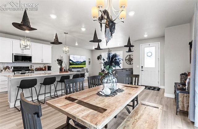 dining space with light hardwood / wood-style floors, a chandelier, and sink