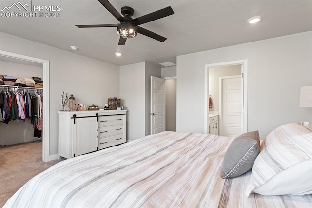 carpeted bedroom with ensuite bath, a spacious closet, ceiling fan, and a closet