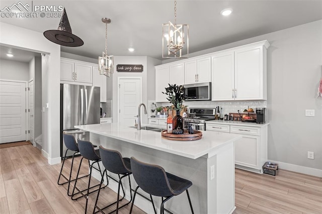 kitchen featuring sink, appliances with stainless steel finishes, an island with sink, decorative backsplash, and white cabinets