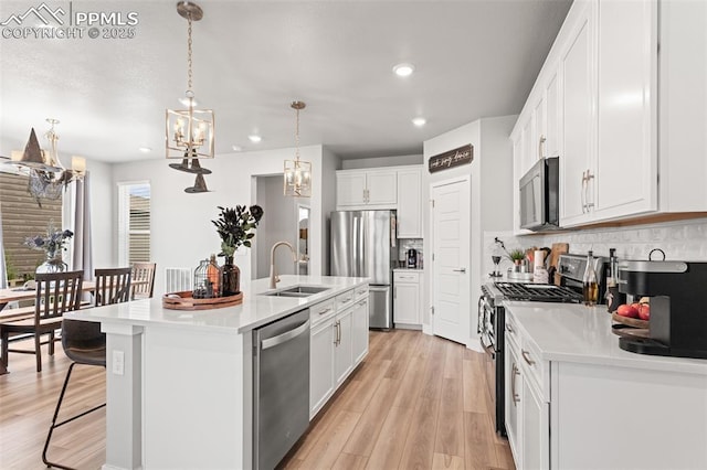 kitchen featuring white cabinetry, appliances with stainless steel finishes, a kitchen island with sink, and sink