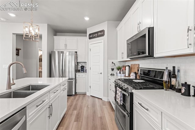 kitchen featuring hanging light fixtures, white cabinetry, appliances with stainless steel finishes, and sink