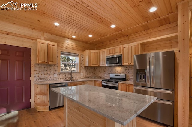 kitchen with appliances with stainless steel finishes, a center island, sink, and light stone countertops