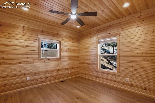 spare room with wood-type flooring, wooden walls, wooden ceiling, and ceiling fan