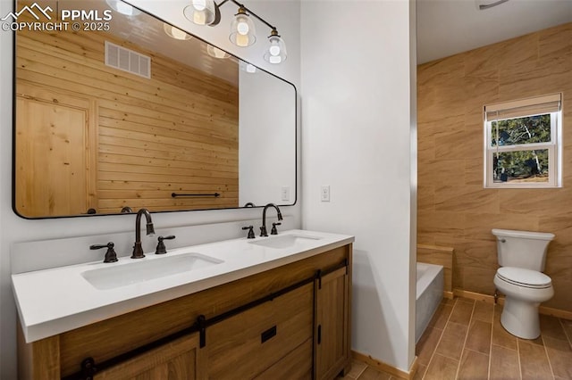 bathroom with a tub to relax in, vanity, and toilet