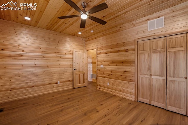 unfurnished bedroom featuring hardwood / wood-style floors, wood ceiling, and wooden walls