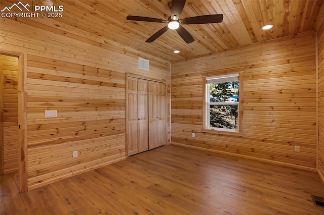 unfurnished bedroom featuring wood ceiling, ceiling fan, hardwood / wood-style floors, and wood walls